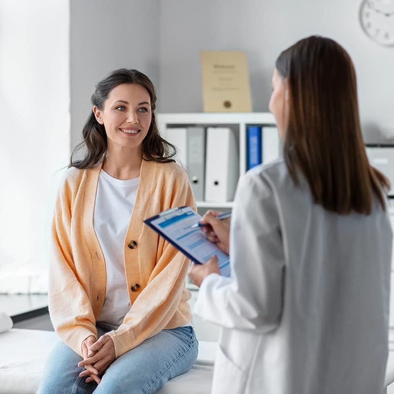 A physician smiling with an older adult patient during a primary care visit.